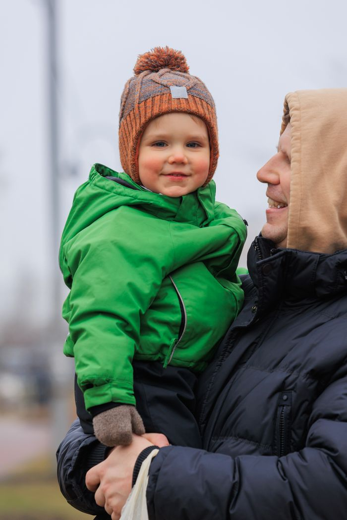 Father and smiling child enjoying a winter day outdoors, dressed warmly.