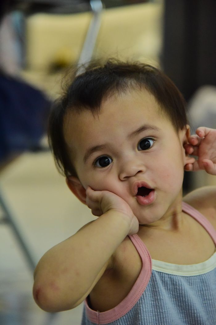 Cute baby making a surprised expression indoors, adding playful charm to the scene.